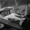 black and white photo of two hands resting on a book that is on a speaker's lectern